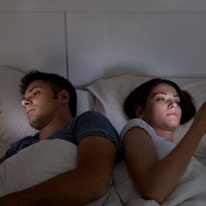 Mann und Frau gucken spätabends auf ihr Smartphone.