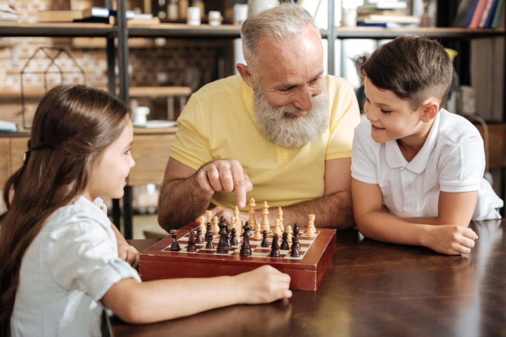 Älterer Mann spiel mit Kindern Schach.
